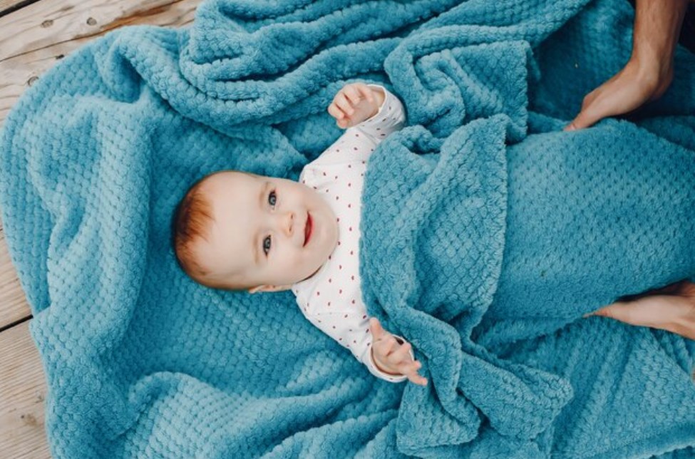 a smiling baby under a blue blanket