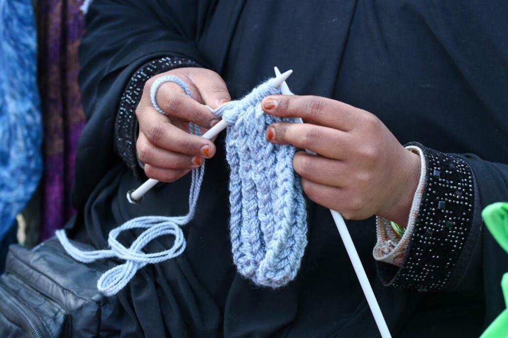 a woman holding a plastic knitting needle in her hands