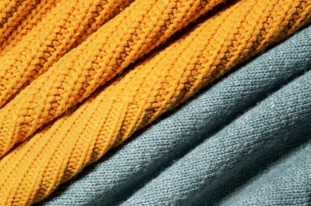 Close-up of yellow and blue stacked knit fabrics with ribbed textures