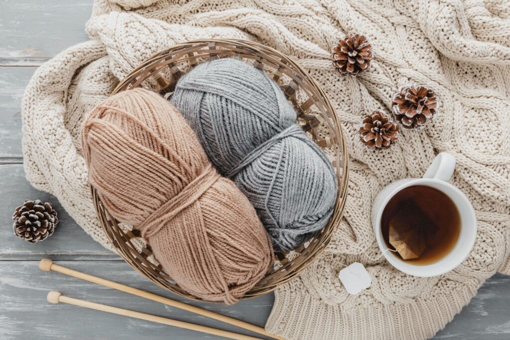 Top view of tea mug and yarn in basket with pine cones