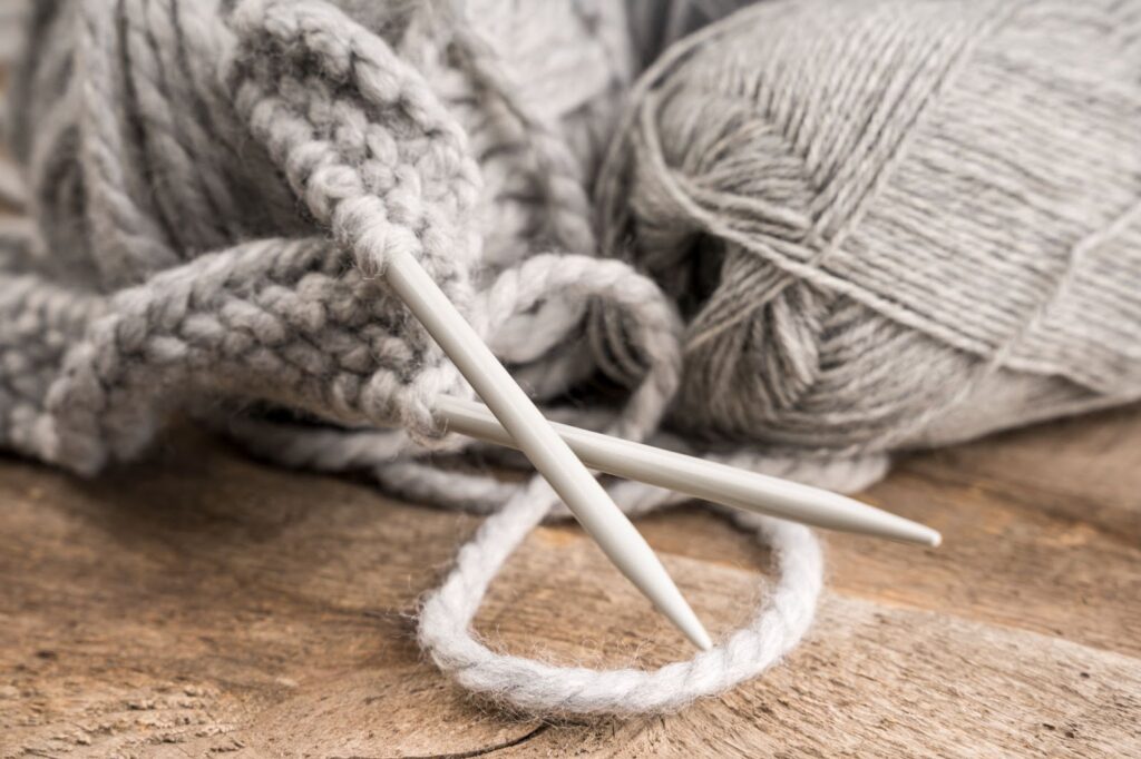 Close up of gray wool and plastic crocheting needles