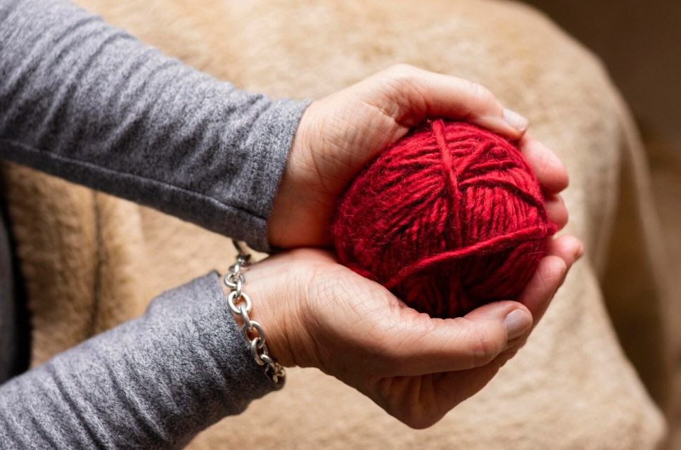 a person holding a red yarn ball for knitting