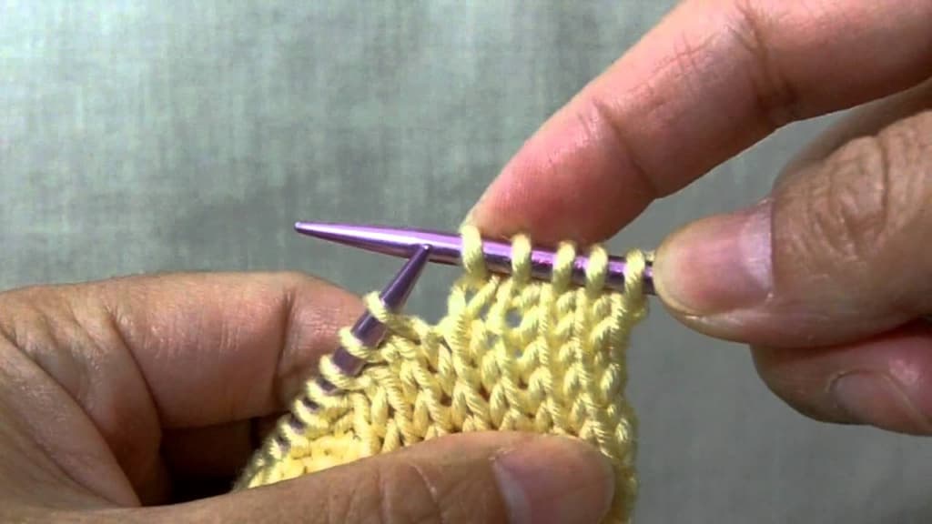 A man knits with yellow yarn