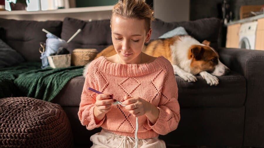 Woman Crocheting in Home with a Dog