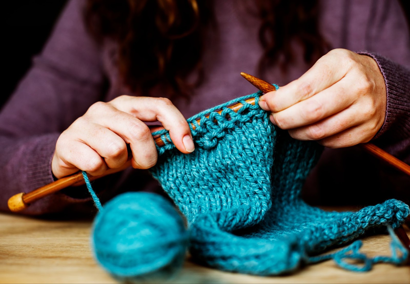 Closeup of woman knitting on wooden table